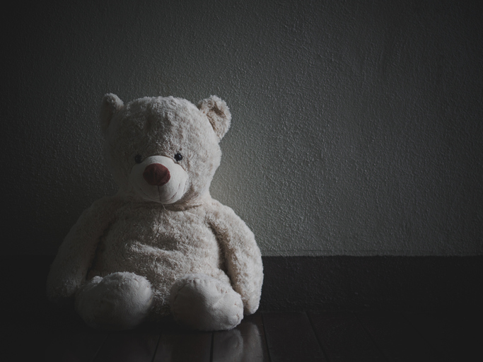 Lonely Teddy Bear Sitting in the dark room (Concept about love)